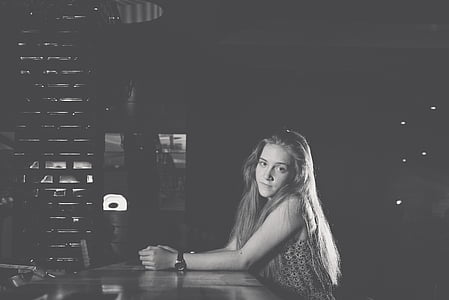 grayscale photo of woman sitting near bar counter thumbnail