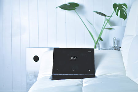 black laptop computer on white bed thumbnail