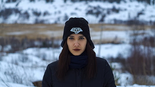 selective focus photography of woman wearing black Diamond Supply Co. knit cap and black knit sweater standing on snow covered ground at daytime thumbnail