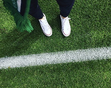 person wearing white low-top sneakers standing on grass thumbnail
