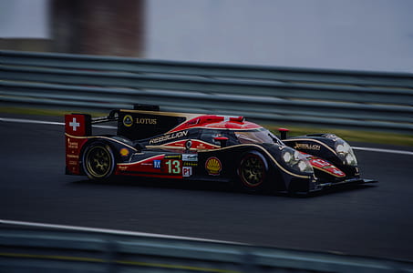 black, red, and gold Lotus racing car on top of racing track thumbnail