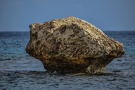 large brown rock in body of water thumbnail