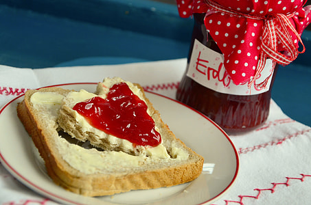 bread with hearth shaped designed on top of white ceramic saucer behind of red glass bottle thumbnail
