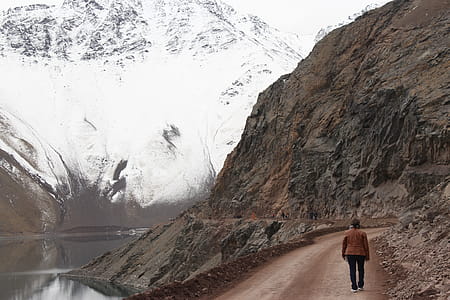 Woman With Brown Jacket Walking Beside Body of Water thumbnail