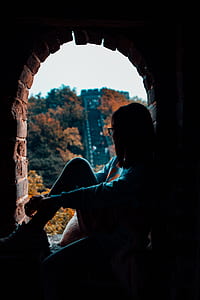 silhouette photography of girl sitting in front of trees thumbnail