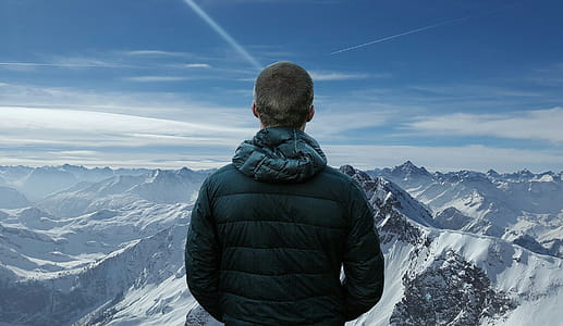 Photo illustration of man standing on top of a mountain in snowy peaks. thumbnail