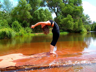 woman standing on ground bending her body surrounded by body of water thumbnail