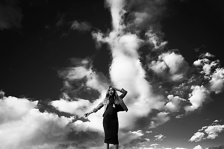 low angle grayscale photo of woman under cumulus clouds thumbnail