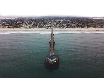 brown wooden dock on seashore near city houses during daytime thumbnail