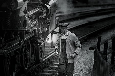 grayscale photo of man beside train thumbnail