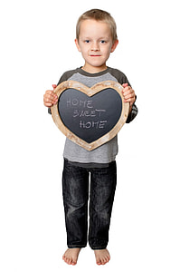 boy hodling heart shaped wooden chalk board with Home Sweet Home written letter thumbnail