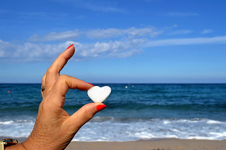 person holding heart-shaped white stone thumbnail