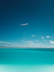 commercial airplane in flight above blue ocean thumbnail