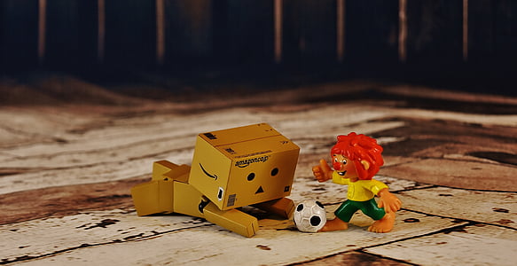 brown cardboard box figurine playing with soccer man figurine thumbnail