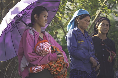 woman carrying baby while holding umbrella thumbnail