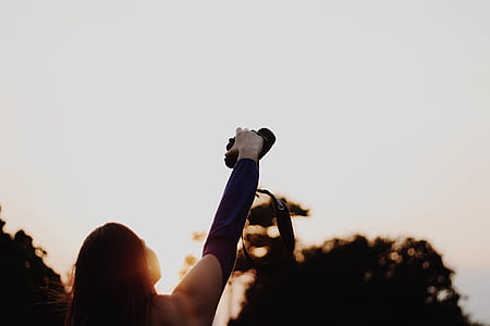 woman holding DSLR camera focusing on the sky thumbnail