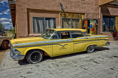 classic yellow sedan taxi cab parked near concrete building thumbnail