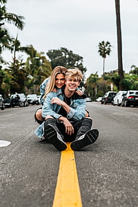 man and woman smiling while sitting in the middle of the road thumbnail