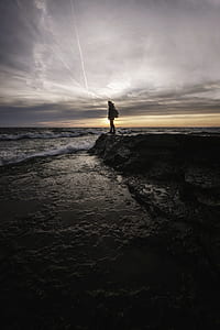 silhouette photography of person standing on shore thumbnail