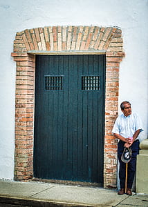 man standing beside black steel gate thumbnail