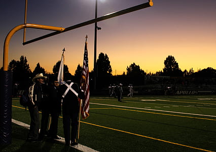 Four People Standing Under on Football Goal during Sunrise thumbnail