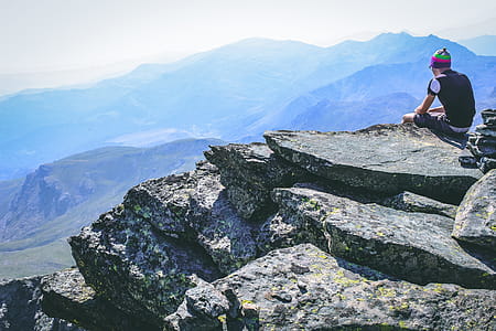 Photography of a Man Sitting on Rock thumbnail