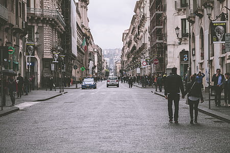 Holding Hand Couple Walking in Street Between Building thumbnail