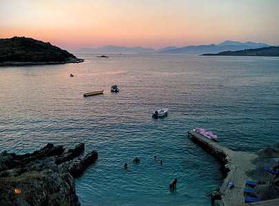 People Swimming in Sea Near Mountain Rocks thumbnail
