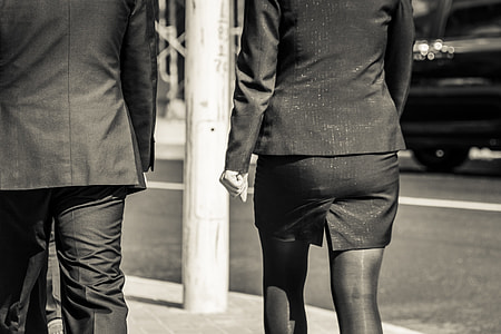 man and woman in black office uniforms walking on the side walk grayscale photo thumbnail