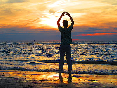 person standing on beach while rising his hand thumbnail