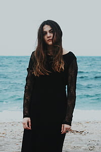 woman wearing black mesh illusion long-sleeved dress standing near seashore at daytime thumbnail