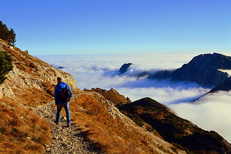 blue in blue jacket on mountain beside sea of clouds thumbnail