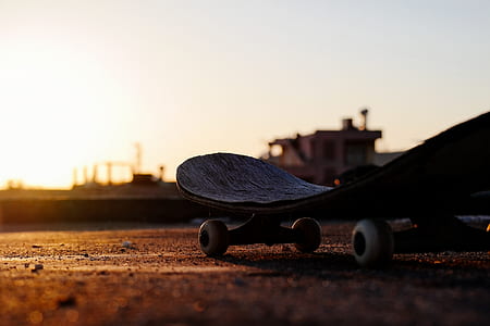low angle view photography of black skateboard on brown soil during golden hour thumbnail