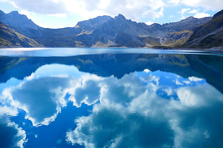 clear blue water reflecting the sky between mountain ranges during day time thumbnail