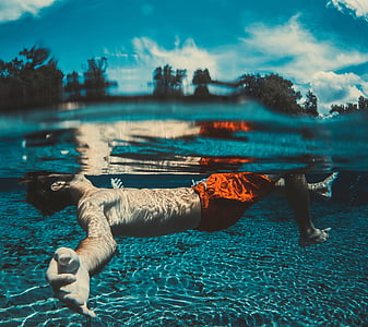 man back floating on body of water during daytime thumbnail