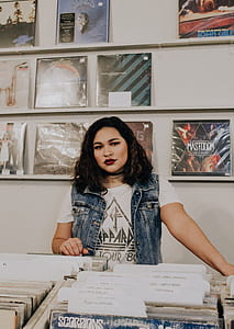 woman wearing blue denim sleeveless shirt standing near vinyl sleeve rack thumbnail