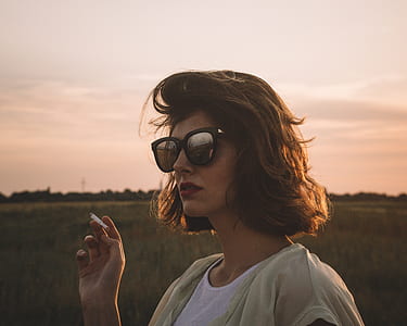 woman holding a cigarette stick during golden hour thumbnail