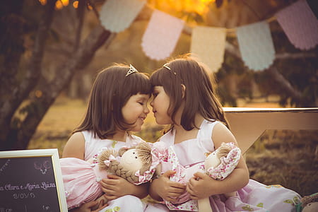 twin sisters holding pink ragdolls during sunset thumbnail