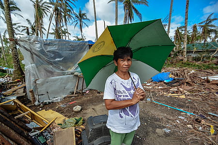 Woman Holding Green, Yellow, and White Umbrella Standing Near Black Crt Tv thumbnail