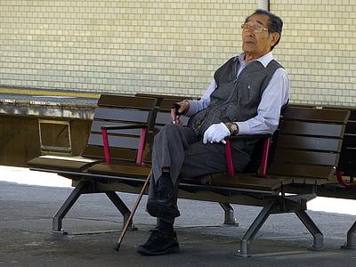 man sitting on black wooden bench holding walking cane thumbnail