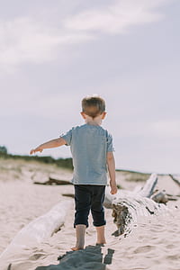 boy wearing gray t-shirt standing near brown sand during daytime thumbnail