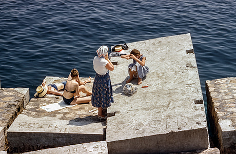 women on gray rock near body of water thumbnail