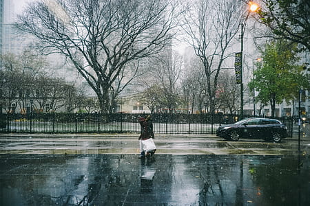 woman crossing street near vehicle and tree thumbnail