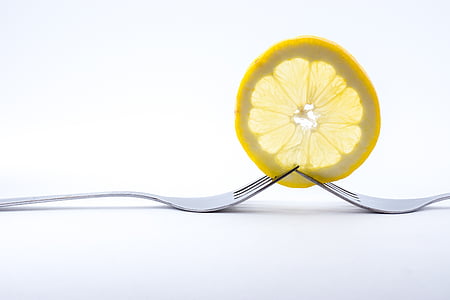 two forks piercing lemon slice on white surface thumbnail