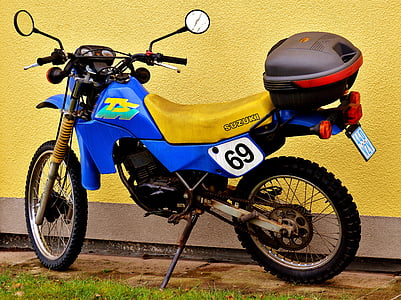 blue and yellow motorcycle parked near yellow painted wall thumbnail