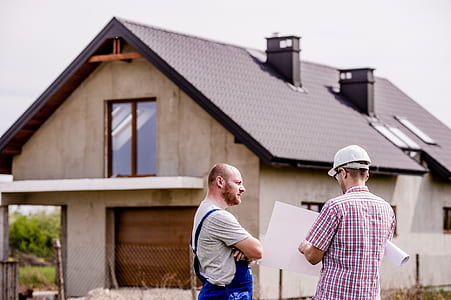 two men standing in front of beige house thumbnail