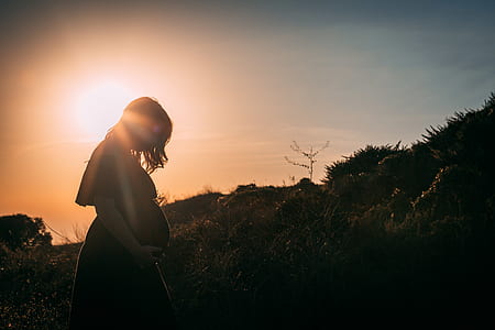 silhouette photography of pregnant woman near plants thumbnail