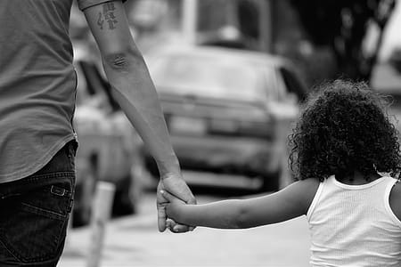 Grayscale Photography of Father and Daughter Holding Each Other While Walking thumbnail
