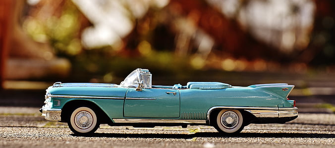 selective focus photography of teal convertible coupe die-cast toy on brown surface thumbnail