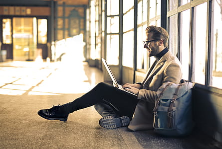 Young Adult Man using a laptop and smiling inside an empty passage during a daytime thumbnail